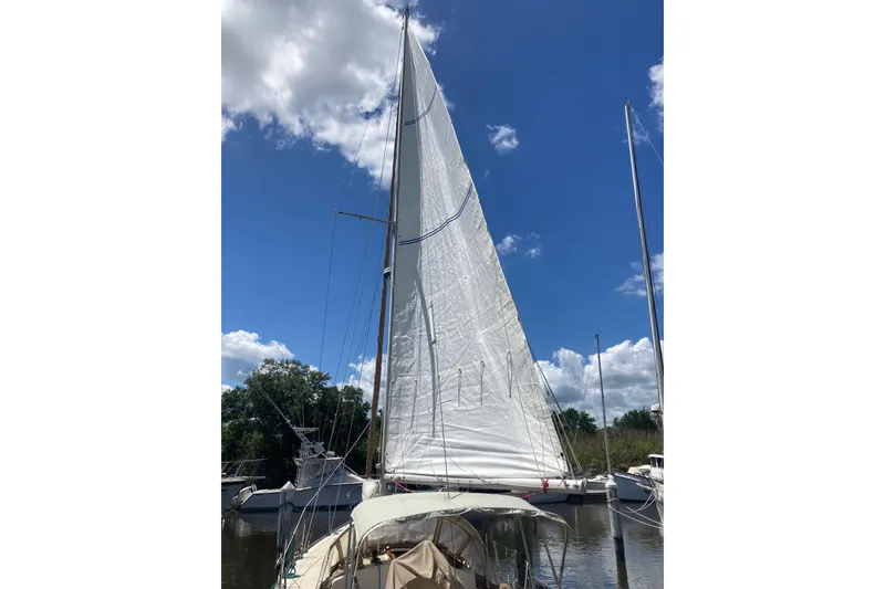 Slide: The Image of 1988 Cape Dory 36 sailboat with raised sails, docked under a clear blue sky. - 22