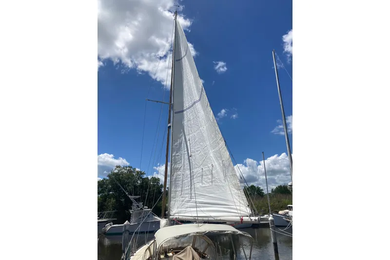 Slide: The Image of 1988 Cape Dory 36 sailboat with raised sails, docked under a clear blue sky. - 24