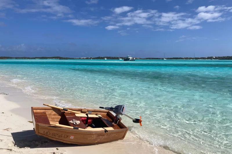 Slide: The Image of Wooden boat on sandy beach with turquoise water, Cape Dory 36, 1988 model in background. - 26