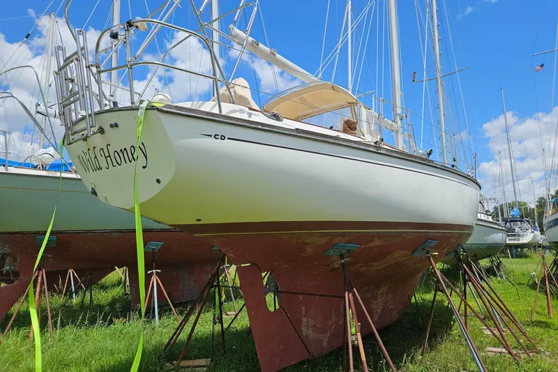 Slide: The Image of 1988 Cape Dory 36 sailboat on land, supported by stands, under a clear blue sky. - 32