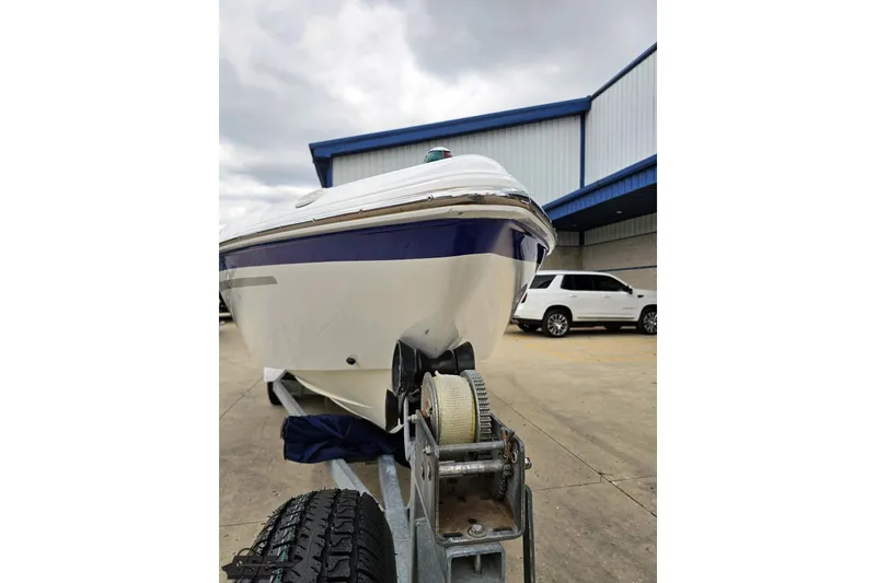 Slide: The Image of 2004 Baja H2X boat on trailer, parked outside a warehouse with a cloudy sky. - 14