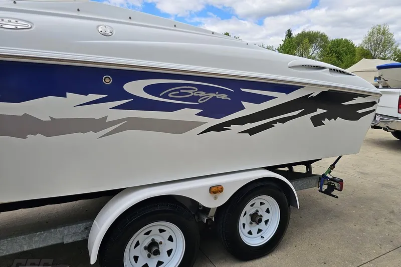 Slide: The Image of 2004 Baja H2X boat on trailer with blue and gray graphics, parked outdoors. - 23