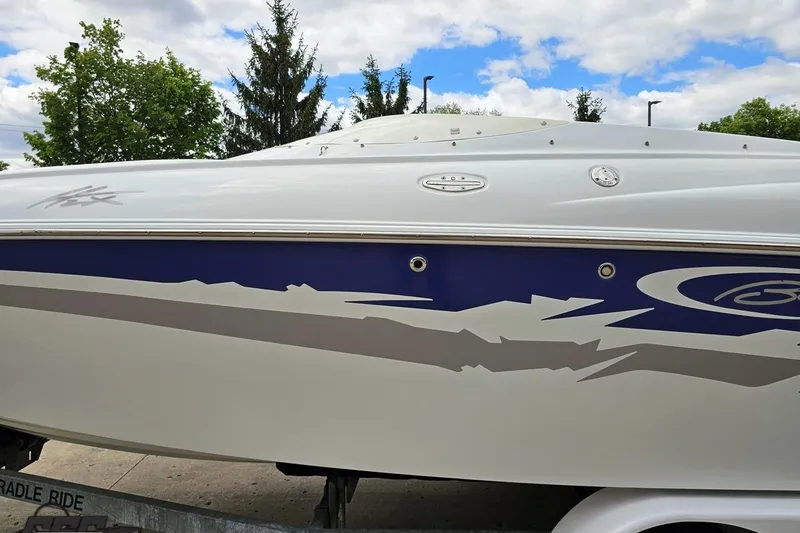 Slide: The Image of 2004 Baja H2X boat with blue and gray graphics, parked outdoors under cloudy sky. - 24