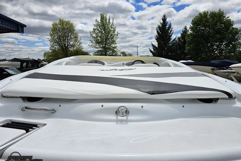 Slide: The Image of 2004 Baja H2X boat with sleek white and black design, parked outdoors under cloudy sky. - 33