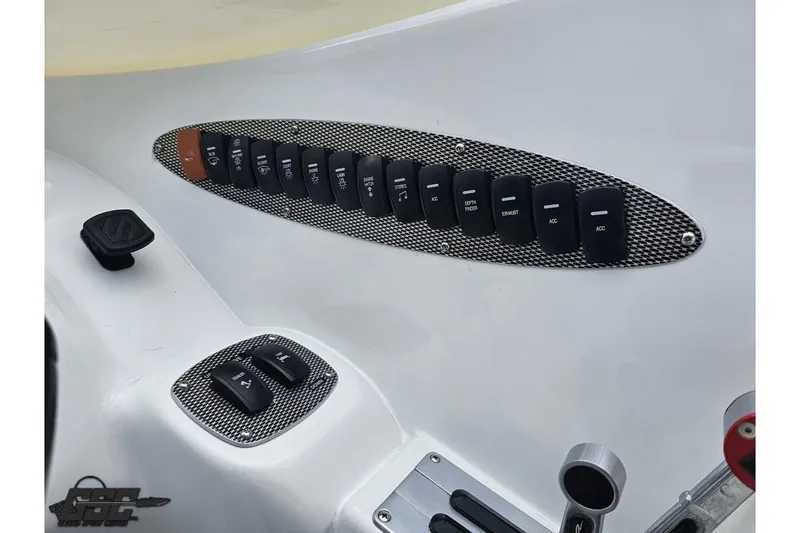 Slide: The Image of Control panel of a 2004 Baja H2X boat with multiple switches and carbon fiber accents. - 60