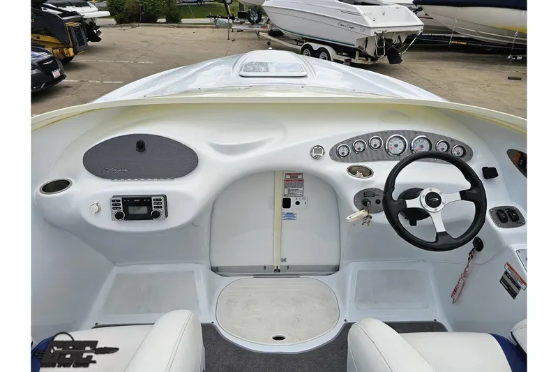Slide: The Image of 2004 Baja H2X boat dashboard with steering wheel and instrument panel in a marina setting. - 61