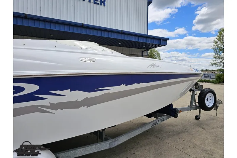 Slide: The Image of 2004 Baja H2X speedboat on trailer, featuring sleek blue and white design under a cloudy sky. - 7
