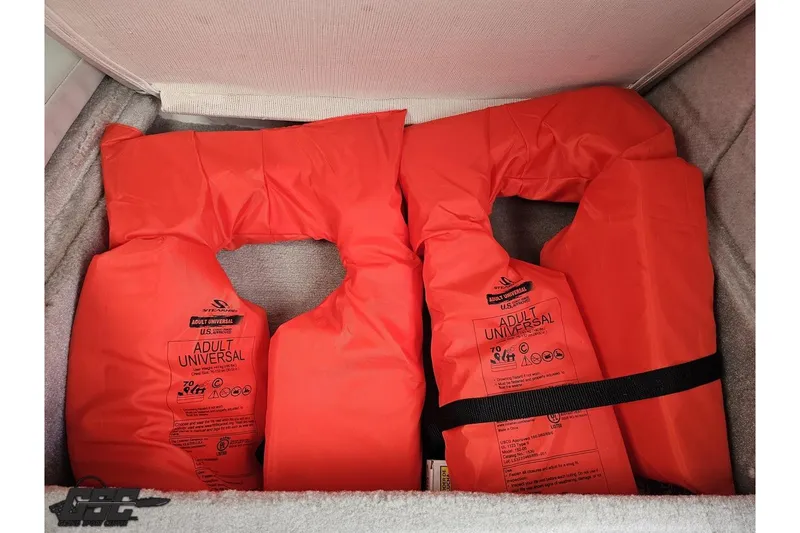 Slide: The Image of Two orange adult universal life jackets in a storage compartment. - 72