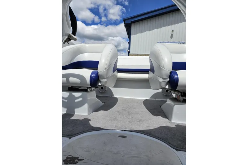 Slide: The Image of 2004 Baja H2X boat interior with white and blue seating under a cloudy sky. - 75