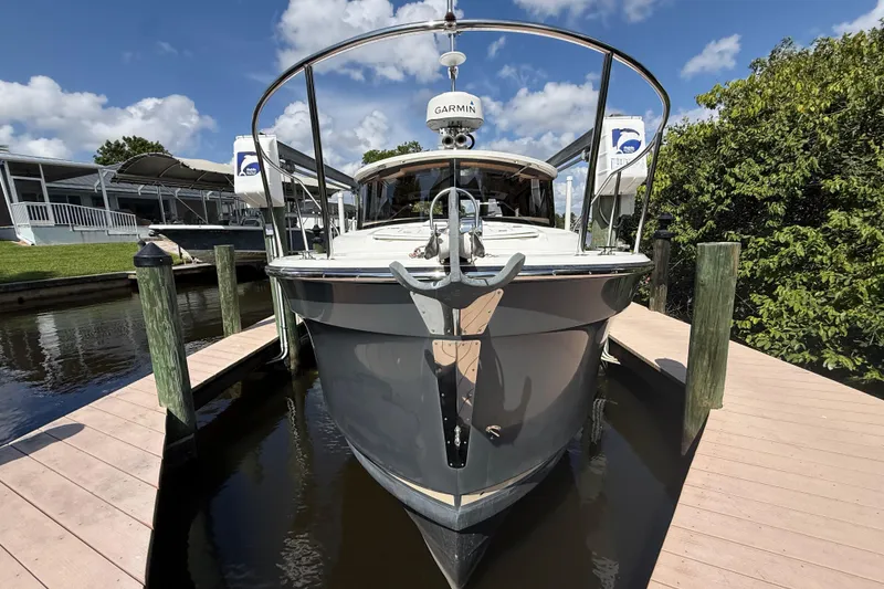 Slide: The Image of 2019 Ranger Tugs R-27 docked, front view with clear skies and lush greenery. - 1