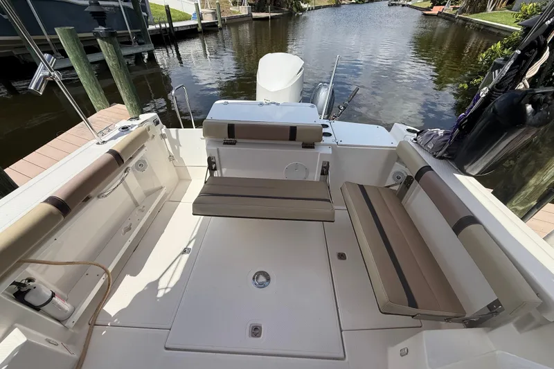 Slide: The Image of 2019 Ranger Tugs R-27 boat interior with seating, docked by a calm waterway. - 14