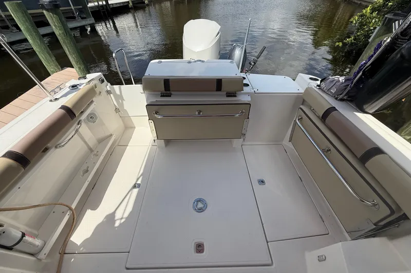 Slide: The Image of 2019 Ranger Tugs R-27 boat deck with seating and storage, docked by water. - 15