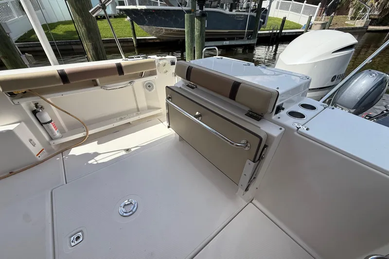 Slide: The Image of 2019 Ranger Tugs R-27 boat interior with seating and storage, docked by the water. - 16