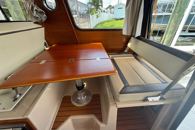 Slide: The Image of Interior of 2019 Ranger Tugs R-27 with wooden table and cushioned seating. - 19