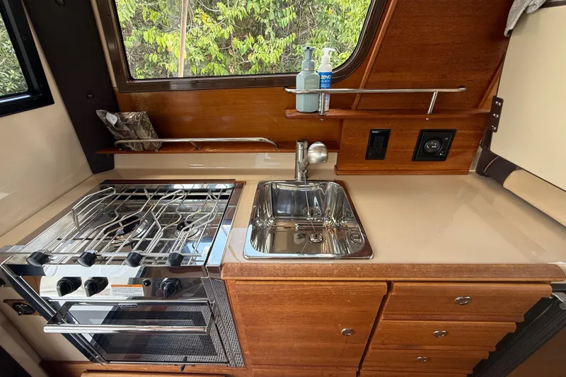 Slide: The Image of 2019 Ranger Tugs R-27 kitchen with stove, sink, and wooden cabinetry. - 21