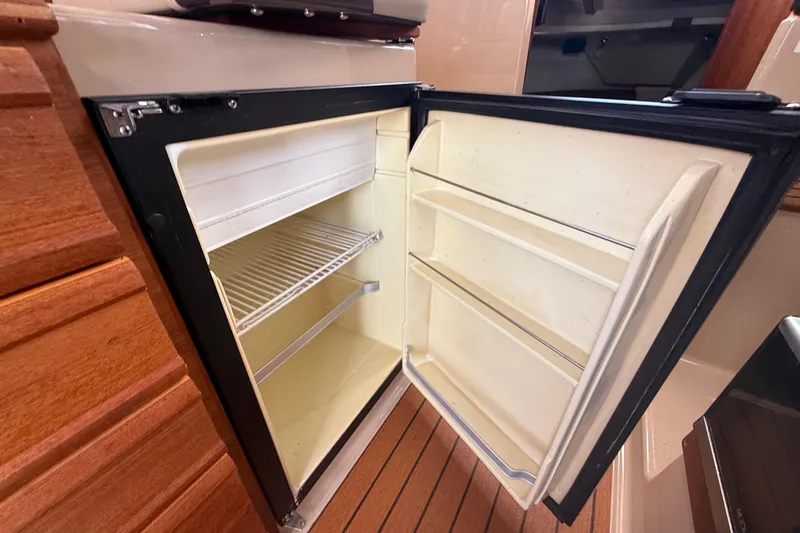 Slide: The Image of Open refrigerator inside 2019 Ranger Tugs R-27 boat, showcasing interior shelves. - 23