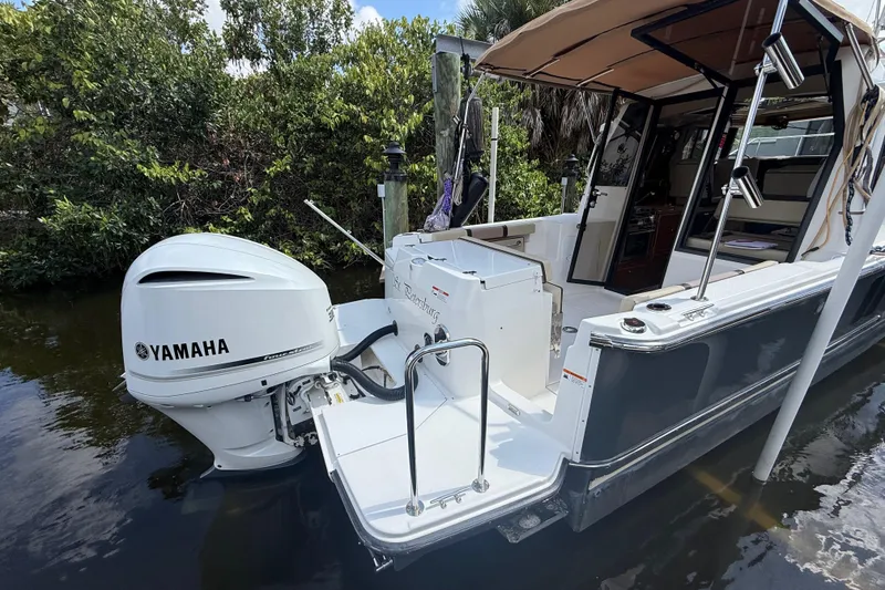 Slide: The Image of 2019 Ranger Tugs R-27 boat with Yamaha outboard motor, docked near lush greenery. - 3