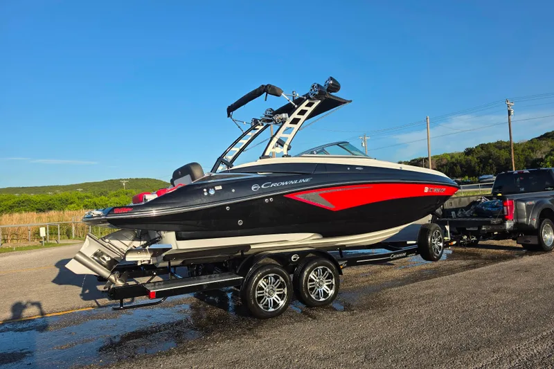 Slide: The Image of 2024 Crownline Eclipse E255 SURF boat on trailer, parked outdoors under clear blue sky. - 6