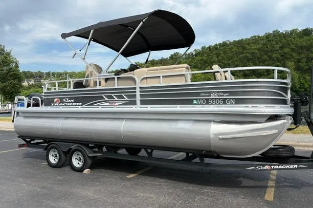 Slide: The Image of 2022 Sun Tracker Fishin' Barge 22 XP3 pontoon boat on trailer in parking lot. - 2