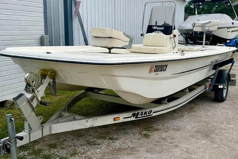 Slide: The Image of 2013 Mako Pro Skiff 17 CC boat on trailer, parked outdoors near a building. - 1