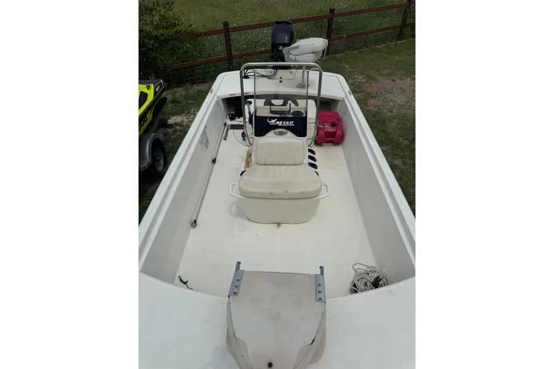 Slide: The Image of 2013 Mako Pro Skiff 17 CC boat with seating and storage, parked on grass. - 4