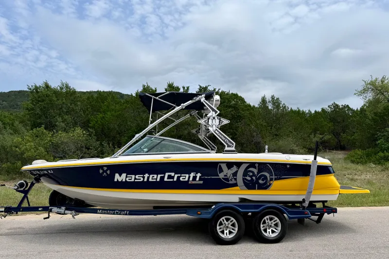 Slide: The Image of 2009 MasterCraft X30 boat on trailer, parked on road with scenic background. - 10