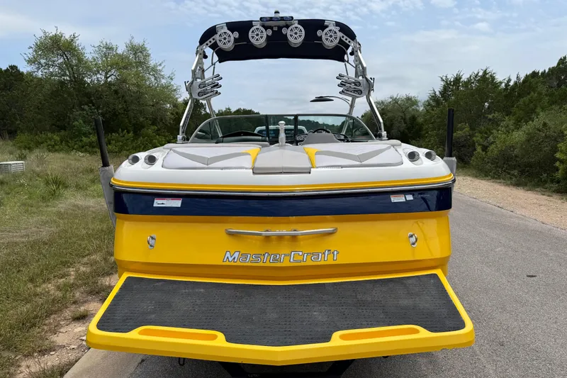 Slide: The Image of 2009 MasterCraft X30 boat with yellow and blue design, parked on a road. - 12