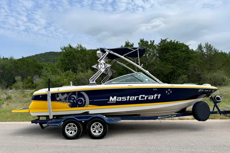 Slide: The Image of 2009 MasterCraft X30 boat on trailer, parked on road with scenic background. - 15
