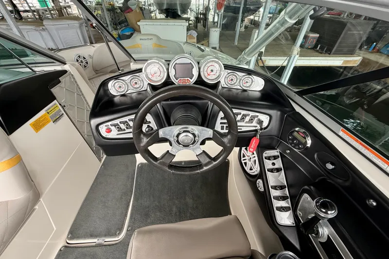 Slide: The Image of 2009 MasterCraft X30 boat dashboard with steering wheel and control gauges. - 25