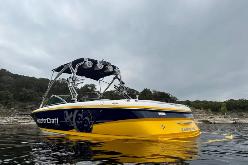 Slide: The Image of 2009 MasterCraft X30 boat with vibrant yellow and blue design on a calm lake. - 6