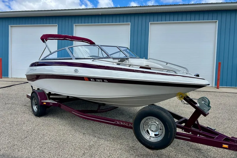 The Image of 2007 Crownline 180 BR boat on trailer, parked outside blue garage. - 0