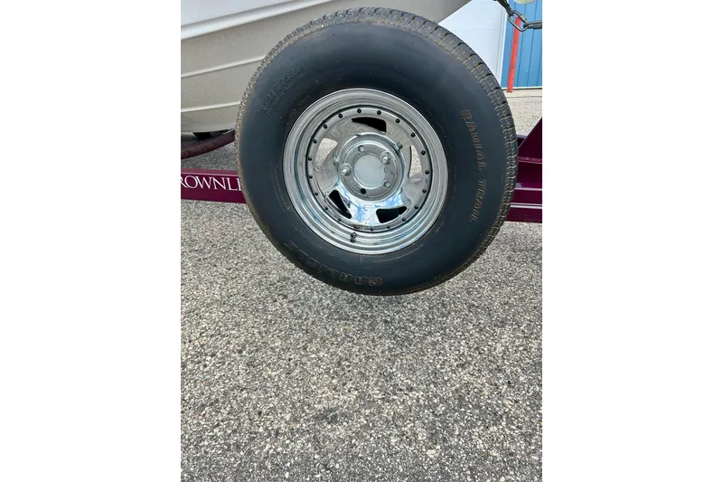 Slide: The Image of Trailer wheel of a 2007 Crownline 180 BR boat on pavement. - 17