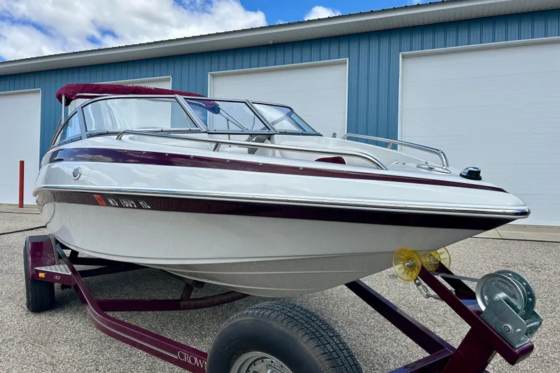 Slide: The Image of 2007 Crownline 180 BR boat on trailer, parked outside blue building under cloudy sky. - 2