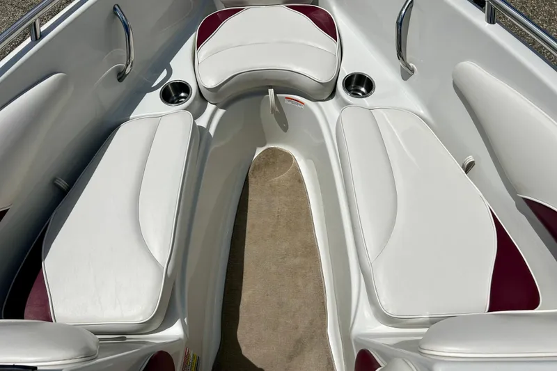Slide: The Image of 2007 Crownline 180 BR boat interior with white and maroon seating, cup holders, and carpeted floor. - 26