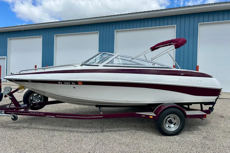 Slide: The Image of 2007 Crownline 180 BR boat on trailer, parked near blue building. - 3