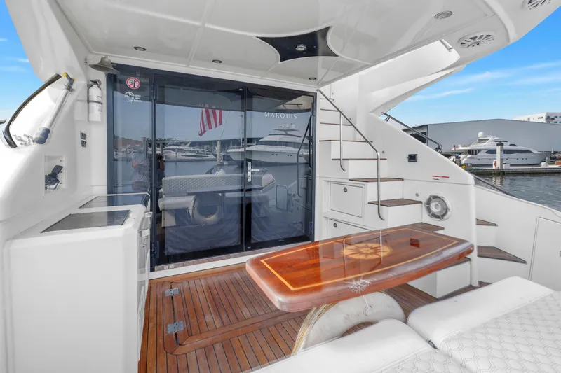 Slide: The Image of Luxurious 2009 Marquis 500 Sport Bridge yacht deck with elegant wood table and marina view. - 17