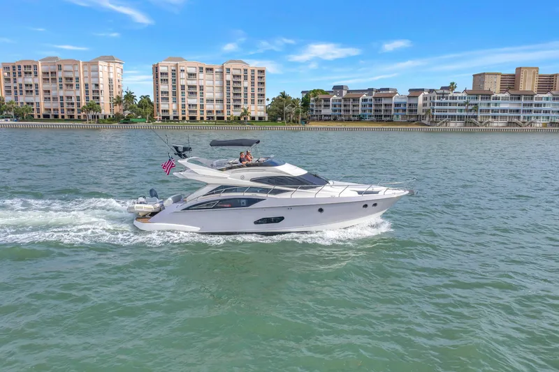 Slide: The Image of 2009 Marquis 500 Sport Bridge yacht cruising near waterfront buildings under a clear blue sky. - 5