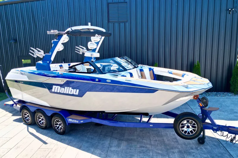 Slide: The Image of 2022 Malibu M240 boat on trailer, sleek design, blue and white color scheme. - 10