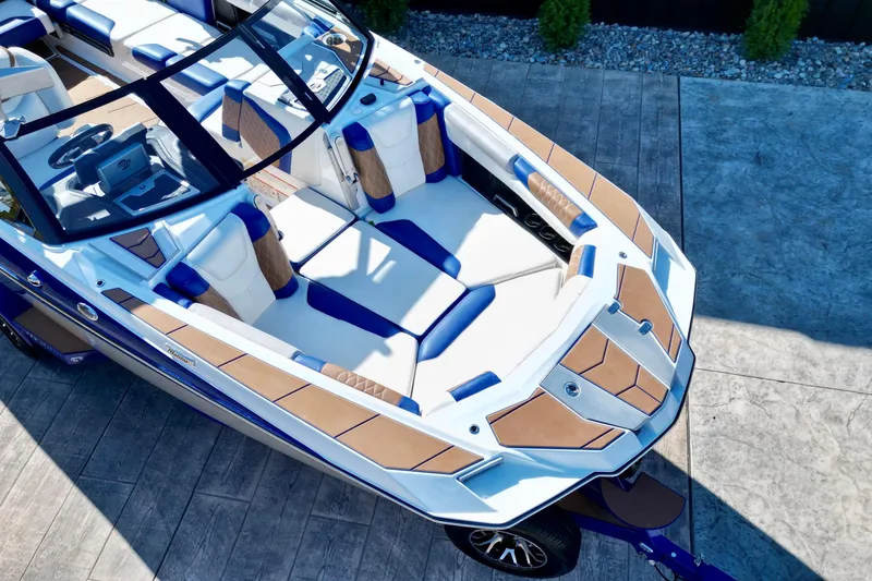 Slide: The Image of 2022 Malibu M240 boat with luxurious seating and sleek design on a concrete surface. - 12