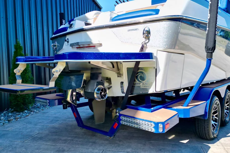 Slide: The Image of 2022 Malibu M240 boat rear view with trailer, showcasing propeller and swim platform. - 16