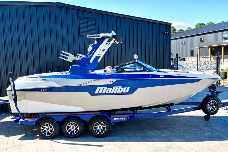 Slide: The Image of 2022 Malibu M240 boat on trailer, parked outside modern building. - 4