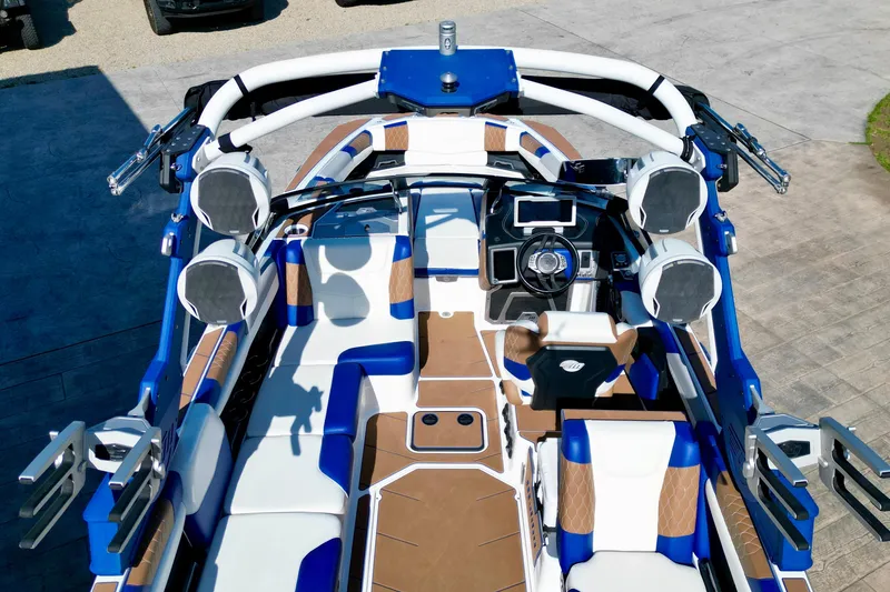 Slide: The Image of 2022 Malibu M240 boat interior with blue and brown seating, advanced dashboard, and speakers. - 7