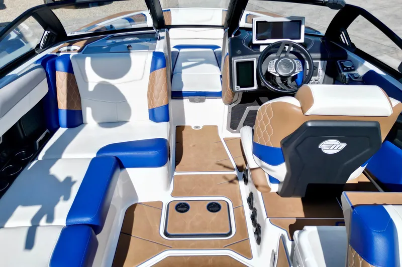 Slide: The Image of 2022 Malibu M240 boat interior with blue and tan seating, modern dashboard, and steering wheel. - 9