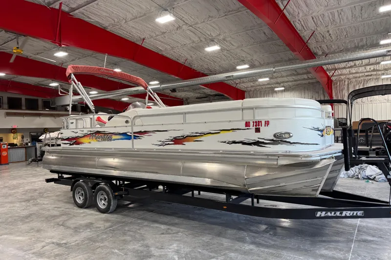 The Image of 2010 Manitou 25 X-Plode pontoon boat on trailer in indoor storage facility. - 1