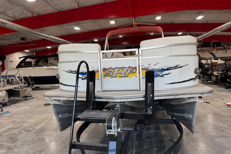 Slide: The Image of 2010 Manitou 25 X-Plode pontoon boat in a showroom with vibrant graphics. - 5
