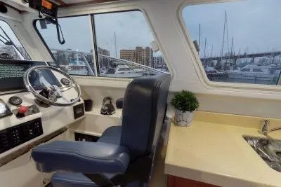 Slide: The Image of 2018 Ocean Sport 33 Roamer interior with helm, blue seat, and marina view. - 7