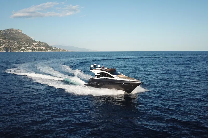 Slide: The Image of Luxurious 2026 Cobrey 52 FLY yacht cruising on open sea with scenic coastline. - 1