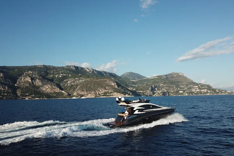 Slide: The Image of Luxurious 2026 Cobrey 52 FLY yacht cruising near scenic coastal cliffs. - 2