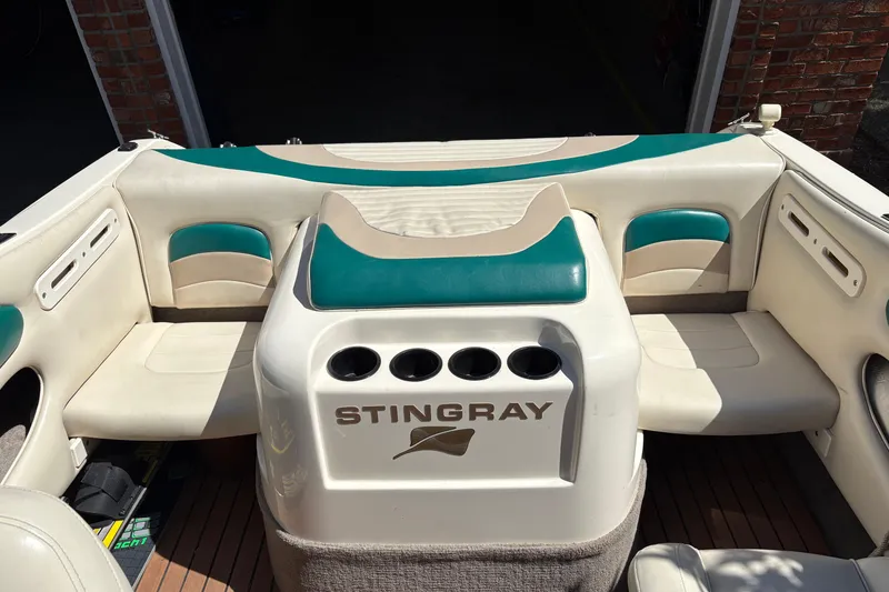 Slide: The Image of 1997 Stingray 200 CS boat interior with white and teal seating, featuring cup holders. - 15