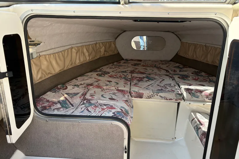 Slide: The Image of 1997 Stingray 200 CS boat cabin interior with patterned cushions and beige curtains. - 19